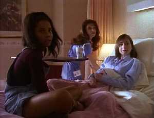 Cassie est dans sa chambre d'hopital, dans son lit, Shannon est assise dessus, elle regarde vers un nouvel arrivant