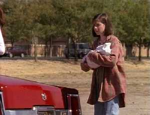 Cassie avec son bb dans les bras derrire la voiture de Monica