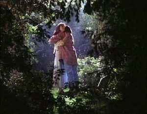 Cassie embrasse Monica dans la lumière au mileu de la forêt obscure