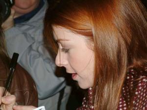 Gros plan de profil d'Alyson signant des autographes